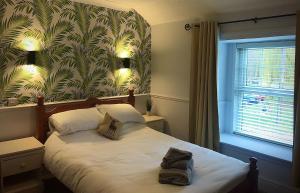RedbourneRed Lion Coaching Inn的一间卧室配有一张带绿叶壁纸的床