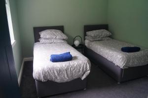 BeithCunninghame 3的两张位于房间的床,上面有两个蓝色枕头