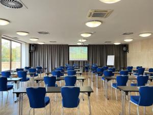 布拉格Blue Orange Resort的一间教室,配有蓝色的桌椅和屏幕