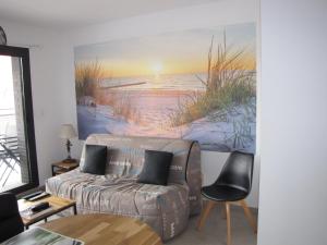拉特斯特德布赫Bel appartement , à 2km du bassin d'Arcachon的客厅配有沙发和海滩绘画