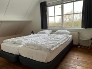 东卡佩勒Het Landhuis的窗户客房内的一张大床