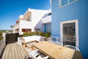 萨格里什卡萨阿祖尔萨格雷斯客房公寓的阳台配有木桌和椅子,公寓是一栋蓝色的建筑。