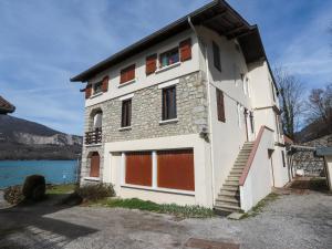 杜萨尔Reflet Bleu du Lac d'Annecy 3 étoiles - Face au lac, Parking gratuit, Paddle board的一座白色的建筑,设有红色的车库门,毗邻湖泊