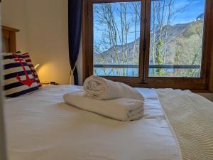杜萨尔Reflet Bleu du Lac d'Annecy 3 étoiles - Face au lac, Parking gratuit, Paddle board的一张带两条毛巾的床和窗户
