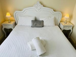 迪斯伯里Heath Cottage Hotel的一张带两个床头柜的白色床,上面有毛巾