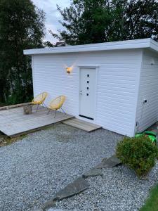 ØsthusvikSjøberg Ferie og Hotell的前面有一个白色的小车库,有两把椅子