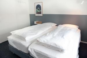 EiðarEiðar - Hostel的配有白色床单的客房内的两张床