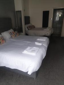 布莱克浦航道酒店的配有白色床单的酒店客房内的两张床