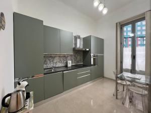 米兰IMHOME - Cadorna House的厨房配有绿色橱柜和玻璃桌
