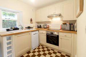 斯基普顿Ivy Cottage的厨房配有白色橱柜和 ⁇ 格地板