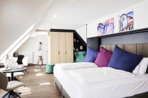 慕尼黑Design- und Kunsthotel München的一间卧室配有一张大床,提供蓝色和紫色枕头