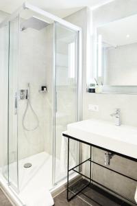 慕尼黑Design- und Kunsthotel München的带淋浴和盥洗盆的白色浴室
