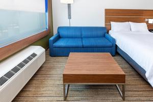 斯塔福德Holiday Inn Express & Suites - Stafford NW - Sugar Land, an IHG Hotel的酒店客房,配有床和蓝色的沙发