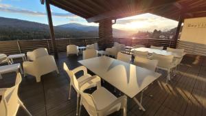 拉姆BayVista, die Bayerwald Lodge的阳台配有白色的桌椅,享有日落美景。