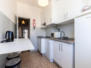 法鲁阿齐索尔法鲁阳光公寓的厨房配有白色橱柜、水槽和2把凳子