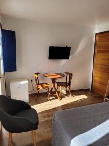 萨尔瓦多Bahia Pelô Hostel的一间配备有桌子和两把椅子及一台电视的房间