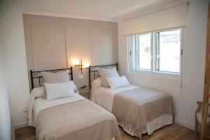 阿丰萨格拉达卡萨马诺洛旅馆的一间卧室设有两张床和窗户。