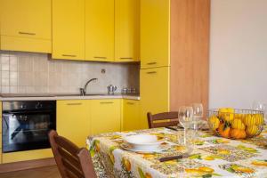 诺托玛丽娜Villa vista mare ~Villa Dafne~的厨房配有黄色橱柜和一张带一碗水果的桌子