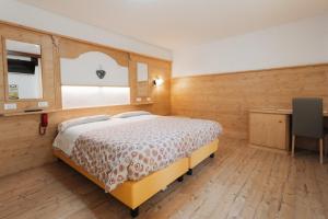 瓦尔迪佐多Hotel Edelweiss的一间卧室配有一张床、一张书桌和一个窗户。