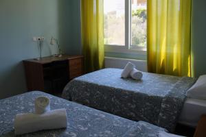 苏尼翁Helen's Sounio Apartments的客房设有两张床和一个带黄色窗帘的窗户。