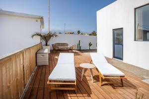 厄尔梅达诺Villa Arizona - 3-bedroom house by the sea的木制甲板配有白色的椅子和桌子