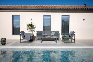 拉宾Villa TonKa with jacuzzi sauna and private pool的庭院设有两把椅子和一张桌子,毗邻游泳池