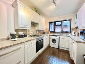 桑当3 Bedroom house - Sandown的厨房配有白色橱柜、洗衣机和烘干机