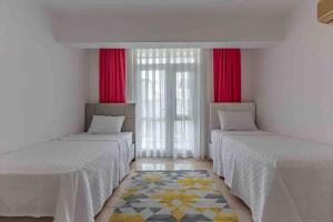 安塔利亚Güneş Villa的配有红色窗帘的客房内的两张床
