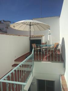 塔维拉Casa 16的阳台配有桌子和雨伞。