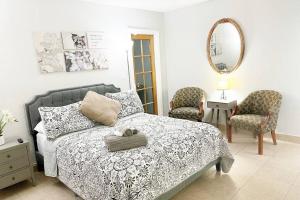 迈阿密Amazing & cozy Duplex near Zoo Miami !的一间卧室配有一张床、两把椅子和镜子