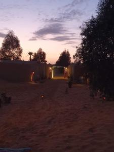 AdrouineSaharaTime Camp的沙漠中的日落,背景是一座建筑