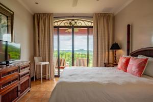 普拉卡海尔Bougainvillea 8211 Luxury Apartment - Reserva Conchal的一间卧室配有一张床、一台电视和一个阳台