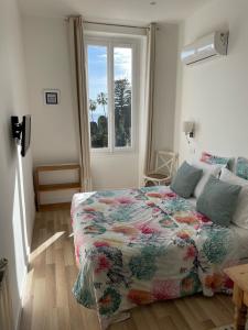 滨海自由城Hôtel La Villa Patricia - Charme et Tradition的一间卧室配有一张带鲜花毯子的床和窗户。
