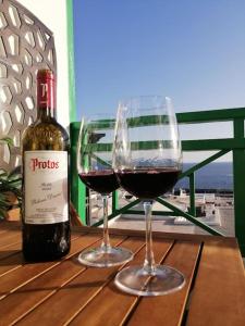 卡门港Portonovo Great Ocean的桌子上放有一瓶葡萄酒和两杯酒