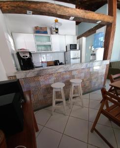 盖比姆Praia de Guaibim - Casa de praia 2Q - 2 suítes com ar - em condomínio a 300m da praia的一间厨房,厨房内设有一个柜台和两个凳子