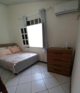 盖比姆Praia de Guaibim - Casa de praia 2Q - 2 suítes com ar - em condomínio a 300m da praia的一间卧室配有一张床、一个梳妆台和一扇窗户。