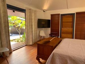 哈皮蒂Luxury & Tropical Villa Te Nunoa, Haapiti Moorea的一间卧室配有一张床、一台电视和一个阳台
