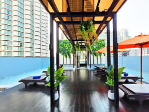 曼谷康帕斯酒店集团素坤逸13巷娜娜柑橘酒店的大楼内带桌子和遮阳伞的游泳池