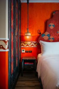 河内Smarana Hanoi Heritage - Hotel and Retreats的一间卧室配有橙色墙壁、一张床和一盏灯