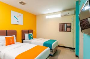 棉兰Sans Hotel Finest Medan的黄色墙壁客房的两张床