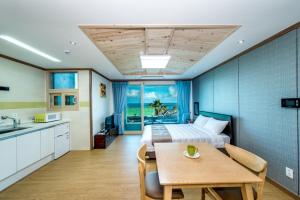 西归浦市Sea and Wave的一间卧室配有一张床铺和一张桌子,还设有一间厨房