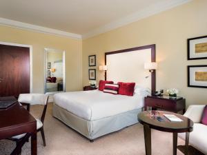 迪拜Mövenpick Grand Al Bustan的酒店客房配有一张床铺、一张桌子和一张书桌。