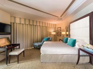迪拜Mövenpick Grand Al Bustan的酒店客房设有一张大床和一张书桌。
