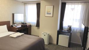 盛冈HOTEL BRIGHT INN MORIOKA的酒店客房设有一张床、一张书桌和窗户。