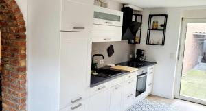 HauModern Apartment Bedburg-Hau的厨房配有白色橱柜和黑色台面