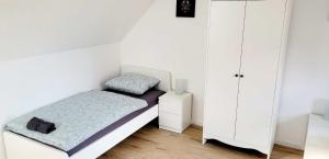 HauModern Apartment Bedburg-Hau的一间白色的小卧室,配有床和橱柜