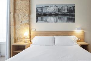 圣塞瓦斯蒂安格罗斯迎宾酒店的一间卧室配有白色床和2个床头柜