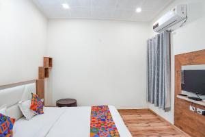 阿格拉FabHotel Sirtaj Suites的一间卧室配有一张床和一台电视