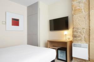 圣塞瓦斯蒂安格罗斯迎宾酒店的一间卧室配有一张床,墙上配有电视