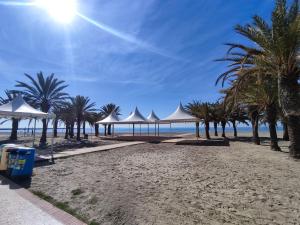 圣波拉Bonita casa al lado de la playa en Santa Pola的一片拥有白色遮阳伞和棕榈树的海滩